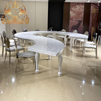 Table à manger élégante et moderne en métal blanc demi-lune avec un design unique de pieds en serpentine pour les mariages, les hôtels et l'extérieur