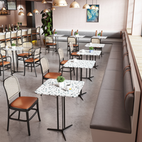Chaises de salle à manger à dossier en cannage avec sièges rembourrés couleur caramel et tables en marbre avec base en piédestal noir pour café-bistro moderne
