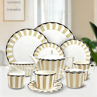 Ensemble de vaisselle en céramique géométrique nordique avec bord doré, assiettes, tasses, cafetière, carafe à lait pour l'hôtellerie et la restauration