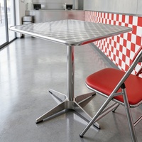 Ensemble table et chaises de style industriel pour restaurant de restauration rapide, comprenant une table réfléchissante et des chaises rembourrées et pliables.