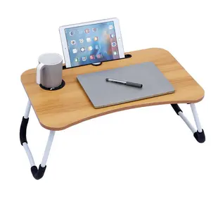 นักเรียนหอพักทำการบ้านเรียนรู้ที่จะเขียนโน้ตบุ๊คโต๊ะเล็กบนเตียงโต๊ะคอมพิวเตอร์ที่เรียบง่าย
