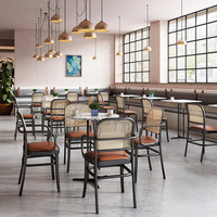 Chaises de salle à manger à dossier en cannage avec sièges rembourrés couleur caramel et tables en marbre avec base en piédestal noir pour café-bistro moderne
