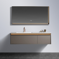 Meuble-lavabo mural gris chaud avec finition or rose, bande de grain de bois, poignée en J dissimulée, vasque intégrée blanche et miroir rétroéclairé par LED