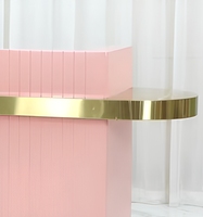 Comptoir de réception rose sur mesure haut de gamme avec panneau à rayures minimalistes et décoration dorée pour salon, spa, centre de beauté et bien-être