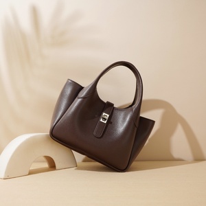 Una borsa in pelle semplice e di nicchia tenuta in mano da donna con un Design grande ed elegante è una borsa A tracolla a spalla singola e sotto le ascelle - Product Image 1
