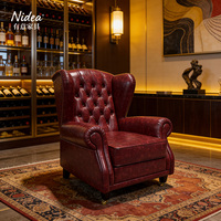Fauteuil Chesterfield de luxe vintage en cuir rouge bordeaux, design capitonné, structure ergonomique et durable, roulettes en laiton, pour club et bar