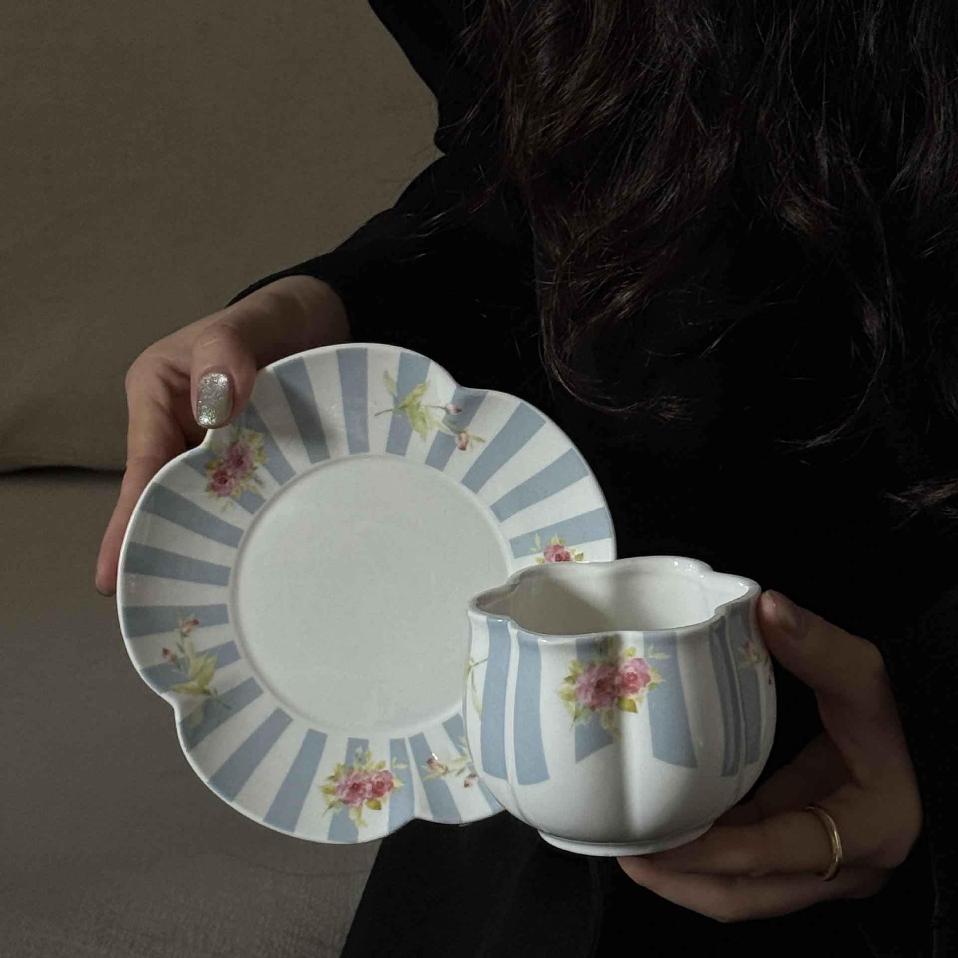 A blue cup with vertical petal stripes and a plate