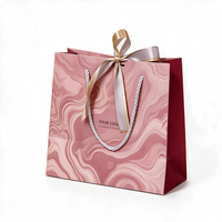 Sac shopping en papier marbré rose avec logo personnalisé, décoration nœud en satin et poignée torsadée en corde pour emballage cadeau de boutique cosmétique