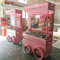 Chariot de présentation mobile haut de gamme rose personnalisé pour cosmétiques et parfums, avec auvent et roues, idéal pour les événements en centre commercial