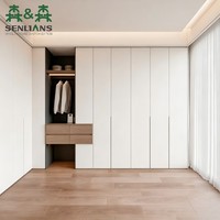 Armoire intégrée moderne et minimaliste avec portes affleurantes blanches, niche ouverte pour suspendre les vêtements et tiroirs en bois.