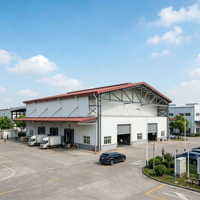 Bâtiment industriel préfabriqué à grande portée en structure acier, avec panneaux gris-bleu et fenêtres latérales longues, pour usine rurale