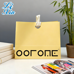 حقيبة ورقية صفراء زاهية بخط أسود جريء، تتميز بمقابض بيضاء متينة، تم التقاطها في نمط حياة بسيط - Product Image 1