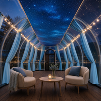 Salle ovale à dôme transparent avec rideaux bleus et vue sur le lac pour la restauration en resort et l'accueil en plein air