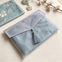 Sac enveloppe élégant de style chinois en organza semi-transparent avec logo personnalisé et fermeture à pompon pour l'emballage de cadeaux vestimentaires