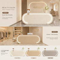 Comptoir de réception ovale moderne et élégant, entièrement recouvert de crème, avec éclairage LED intégré pour salon de beauté et clinique esthétique