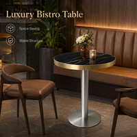 Table de bistrot de luxe en pierre frittée noire avec base carrée sur piétement doré, mobilier commercial pour restaurant