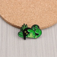 Épingle en émail de créature de forêt enchanteresse-Figure noire parmi les feuilles vertes. Un accessoire fantaisiste pour les amoureux de la nature
