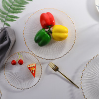 Assiette de présentation moderne et minimaliste en verre transparent avec bordure dorée cannelée, idéale pour les fruits, pour table de salle à manger, événements et fêtes