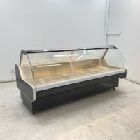 Vitrine réfrigérée moderne en verre incurvé pour la présentation de fromages artisanaux dans les sections de charcuterie des magasins spécialisés en produits alimentaires.
