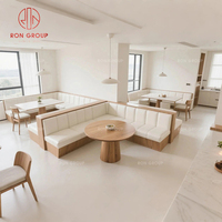 Ensemble de banquette moderne et confortable avec structure métallique incurvée et revêtement en cuir blanc, table ronde en bois pour restaurant ou café