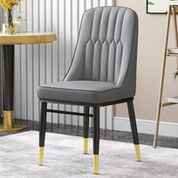 Chaise de salle à manger en similicuir gris raffiné avec coutures en losange, assise moelleuse et pieds à embouts dorés pour une salle à manger contemporaine