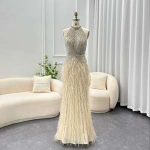 فستان سهرة فاخر من شارون سعيد طراز SS006 مزين بالترتر والخرز والريش بتصميم حورية البحر بلون بيج مع ياقة هالتر وظهر مكشوف لحفلات التخرج والمناسبات الرسمية - Product Image 1