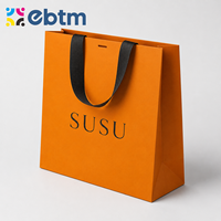 Sacs cadeaux en papier orange de luxe personnalisés en gros avec poignées en ruban noir pour l'emballage de détail
