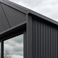 Maison modulaire contemporaine en conteneur avec structure en acier, grandes portes vitrées et plateforme sur le toit