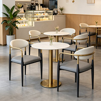 Table ronde en pierre frittée avec structure en métal doré et ensemble de fauteuils en cuir pour café, boulangerie, salon de thé, mobilier commercial