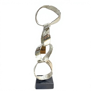 Escultura Moderna de Metal Plateado con Forma de Lazo, Estatua Abstracta de Cintas Entrelazadas Verticales sobre Base Oscura, Decoración de Lujo para el Hogar - Product Image 1