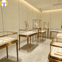 Vitrine à bijoux en verre sur mesure de luxe, cadre en métal doré, éclairage LED, écologique, robuste, personnalisable pour les articles haut de gamme
