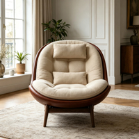 Fauteuil lounge individuel en forme de cocon, capitonné beige, avec structure en fibre de verre marron et pieds en bois massif, pour un espace de vie résidentiel moderne