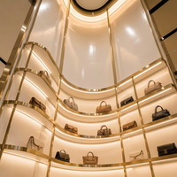 Vitrine de présentation de sacs à main en acier inoxydable doré de luxe sur mesure avec éclairage LED incurvé pour boutique de détail