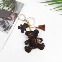 Nouveau porte-clés mignon en forme d'ours, en cuir PU, avec pompon, mini breloque tendance, forme irrégulière, cadeau d'affaires, souvenir, pendentif pour sac de fille