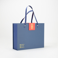 Boîte cadeau de Noël et du Nouvel An bleue, orange et rouge en papier couché avec pelliculage brillant et mat, gaufrage et estampage pour bougies