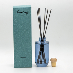 Diffuseur de parfum <span class=keywords><strong>d</strong></span>'ambiance minimaliste en verre cylindrique bleu fumé avec logo personnalisé, bouchon en bois naturel et bâtonnets en fibre noire - Product Image 1