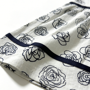 فستان مطبوع بالورود الزرقاء على خلفية بيضاء بالجملة، بدون أكمام، تنورة واسعة، حواف كحلية، ظهر مفتوح، تصميم بفيونكة - Product Image 3