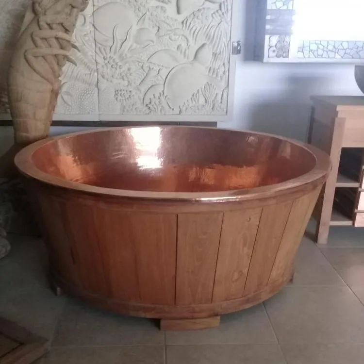 チーク材の浴槽バリと槌で打たれた丸い銅の浴槽