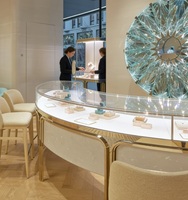 Vitrine à bijoux de luxe en forme de S, incurvée, de haute qualité et durable |   Base en pierre crème avec cadre en métal doré |   Vitrine en verre LED