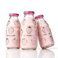 Les marques de boissons bio utilisent des bouteilles de lait en verre transparent ergonomiques et rainurées avec des bouchons à vis en métal rose fuchsia.