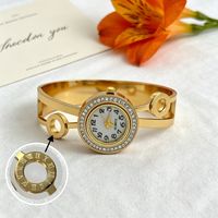 Montre bracelet pour femme à cadran rond incrusté de diamants, motifs ajourés multiples, bracelet en acier titane doré brillant