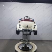 Chaise de barbier pour enfants de style rétro dans le salon, Rolls cream convertible avec siège rouge sur base brillante.