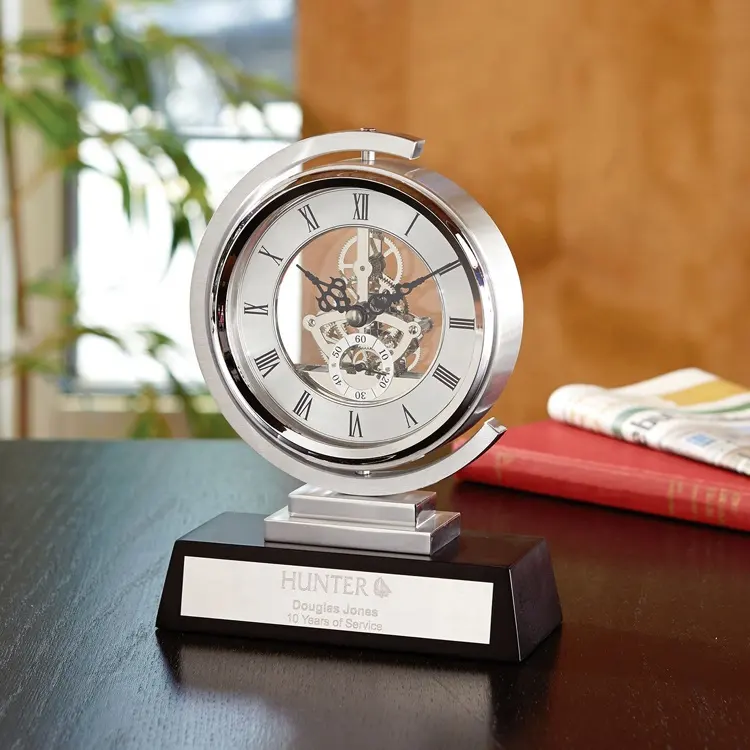 Relógio de mesa de prata do metal que gira 360 graus sobre base de madeira preta
