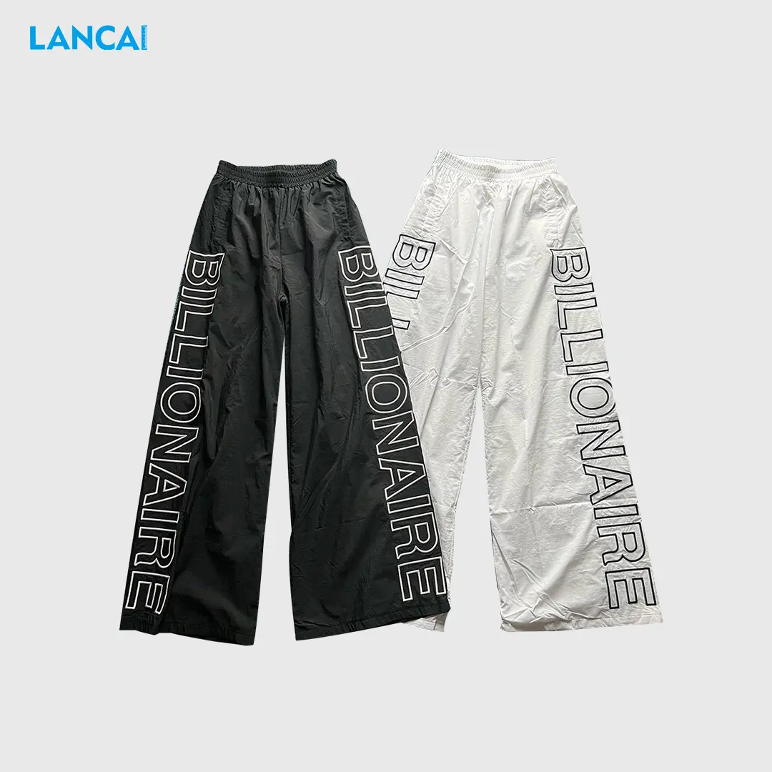 Pantalones de nailon con letras impresas para hombre Color sólido OEM Pantalones de poliéster para hombre Cintura elástica Pantalones sueltos transpirables informales Flair