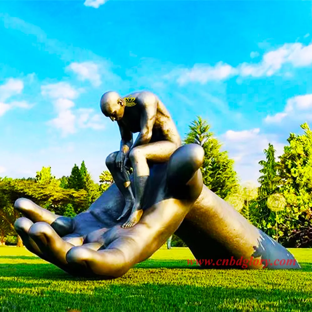 Tuin Metalen Kunst Ornamenten Bronzen Sculptuur Van Een Naakte Man Zittend Op Een Grote Hand