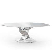 Table à manger au design moderne avec des lignes audacieuses et une forme facetée unique, idéale pour appartement ou villa, en acier inoxydable.