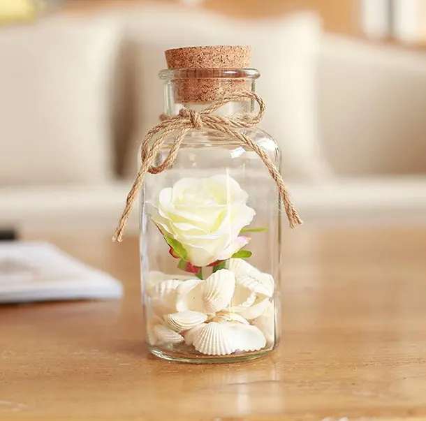 乾いた花や紙の星や麻の装飾とラベルが付いたシェル用の素敵なガラス瓶