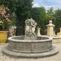 Piscina antica di marmo di colore scuro che gioca la fontana delle statue del cherubino per il paesaggio