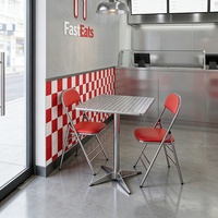 Ensemble table et chaises de style industriel pour restaurant de restauration rapide, comprenant une table réfléchissante et des chaises rembourrées et pliables.