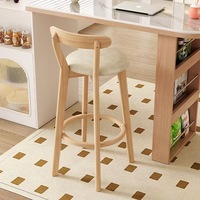 Tabouret de bar à pieds hauts en bois clair avec siège moderne minimaliste rembourré et repose-pieds rond. Baravec une conception arquée de dossier.